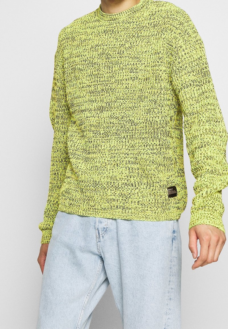 Suéter de punto amarillo neón con un patrón texturizado, escote redondo y mangas largas. Presenta una pequeña etiqueta de la marca en el dobladillo inferior.