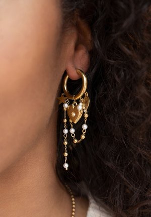 Gold hoop earring with cascading chains featuring heart, star, and circular charms. Accented with white pearls and small gold beads.