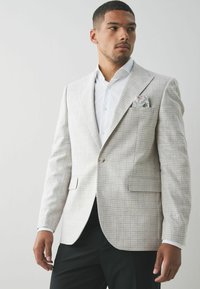 Hellgrau gemusterter Blazer mit slim Fit, der über einen einzigen Knopfverschluss und zwei Vordertaschen verfügt. Inklusive einfarbigem Taschentuch mit Blumenmuster.