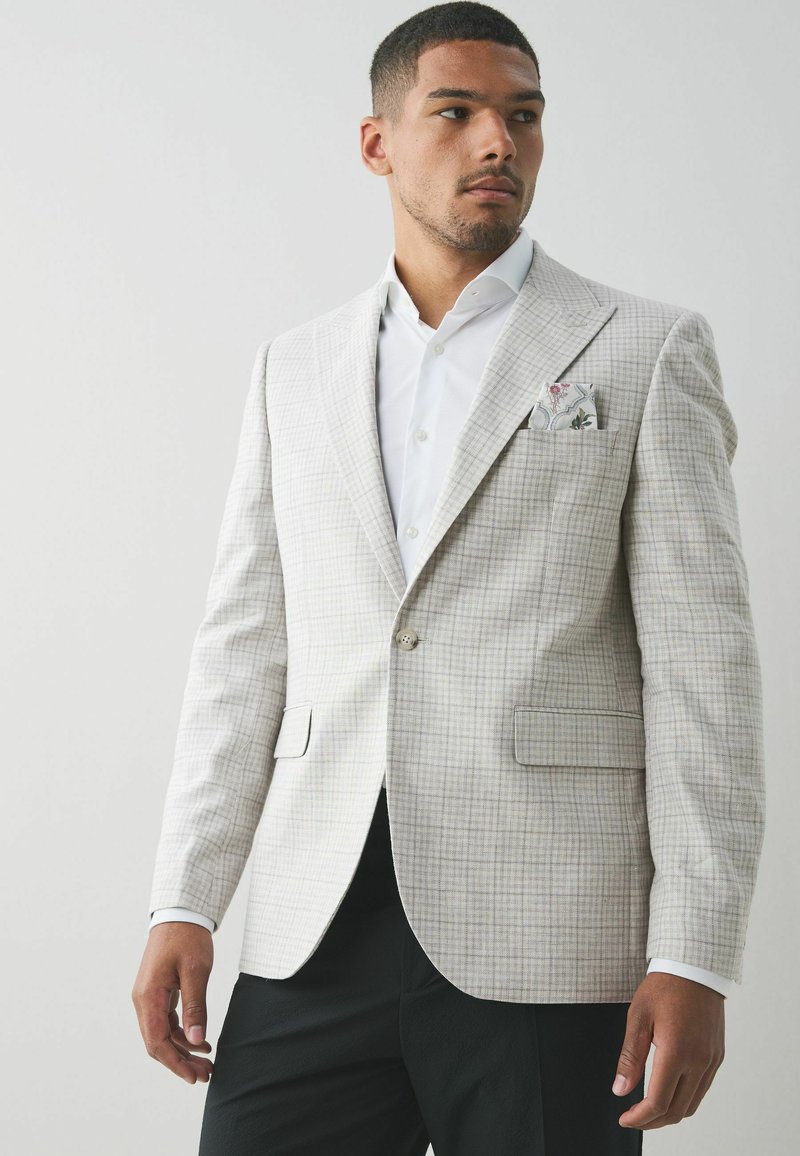 Hellgrau gemusterter Blazer mit slim Fit, der über einen einzigen Knopfverschluss und zwei Vordertaschen verfügt. Inklusive einfarbigem Taschentuch mit Blumenmuster.
