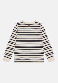 Langermet skjorte i kremfarge med marineblå horisontale striper, rund halslinning og et lite stoffmerke i beige bak. Laget av bomull, myk tekstur.