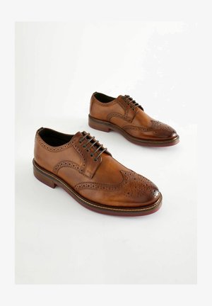 Brown leather Oxford shoes with perforated detailing, lace-up closure, and a rounded toe. Smooth texture and contrasting sole.
