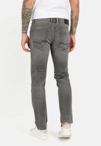 Grå denim jeans med en slim fit, der har baglommer, subtil fading og en lædermærke. Kombinationen med hvide sneakers.