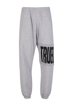 Pelēki sporta bikses ar elastīgu jostasvietu, sašaurinātām kājām un lielu melnu "TRUER" grafiku sānos. Mīksts kokvilnas maisījuma materiāls.