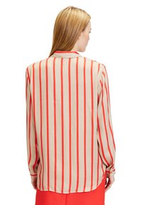 Beige long-sleeve shirt featuring vertical red stripes, buttoned cuffs, and a relaxed fit. Smooth fabric with a back yoke seam detail.