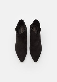 Stivaletti neri in suede con punta affusolata, cerniere laterali e una texture liscia. Design minimalista che mette in evidenza una silhouette elegante.