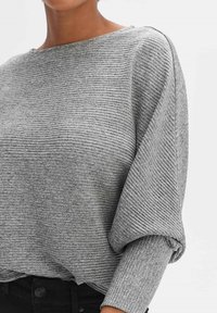 Top grigio a coste con scollatura ampia, maniche oversize e superficie testurizzata, abbinato a pantaloni neri a vita alta.