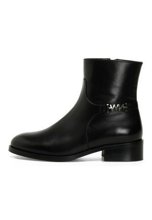Bottine en cuir noir avec un bout arrondi, un petit talon carré et une sangle latérale avec des éléments en métal. Texture lisse et design minimaliste.