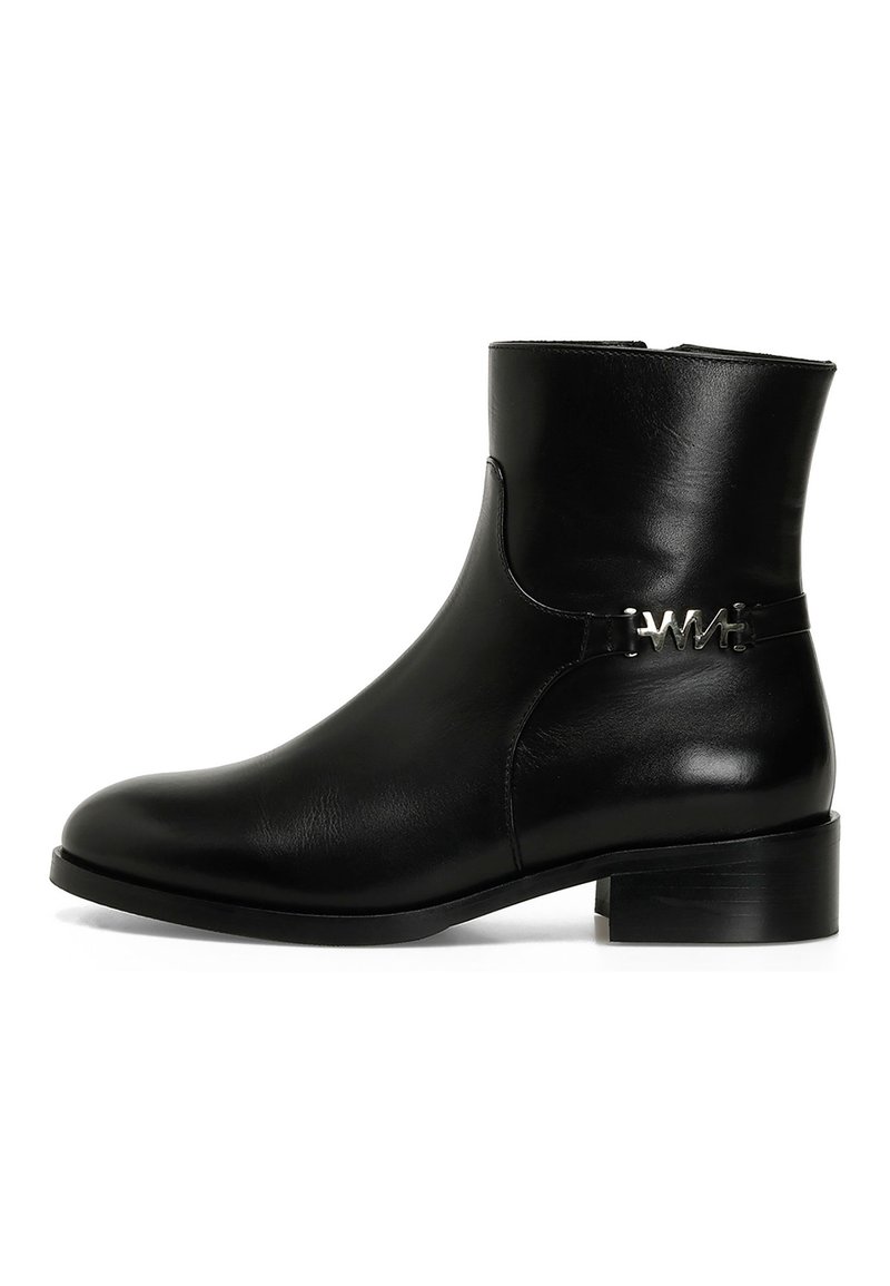 Must musta ankle boot ümmarguse varbaga, madalate plokk-kannaga ja külglastri, millel on metallist riistvara. Sile tekstuur ja minimaalne disain.