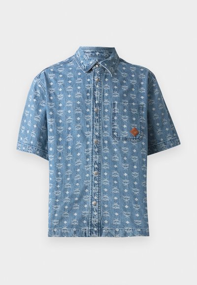 Světle modrá džínsová košile s krátkým rukávem, s bílým geometrickým vzorem po celém povrchu, přední kapsou a hnědým logem, obsahující kovové knoflíky.