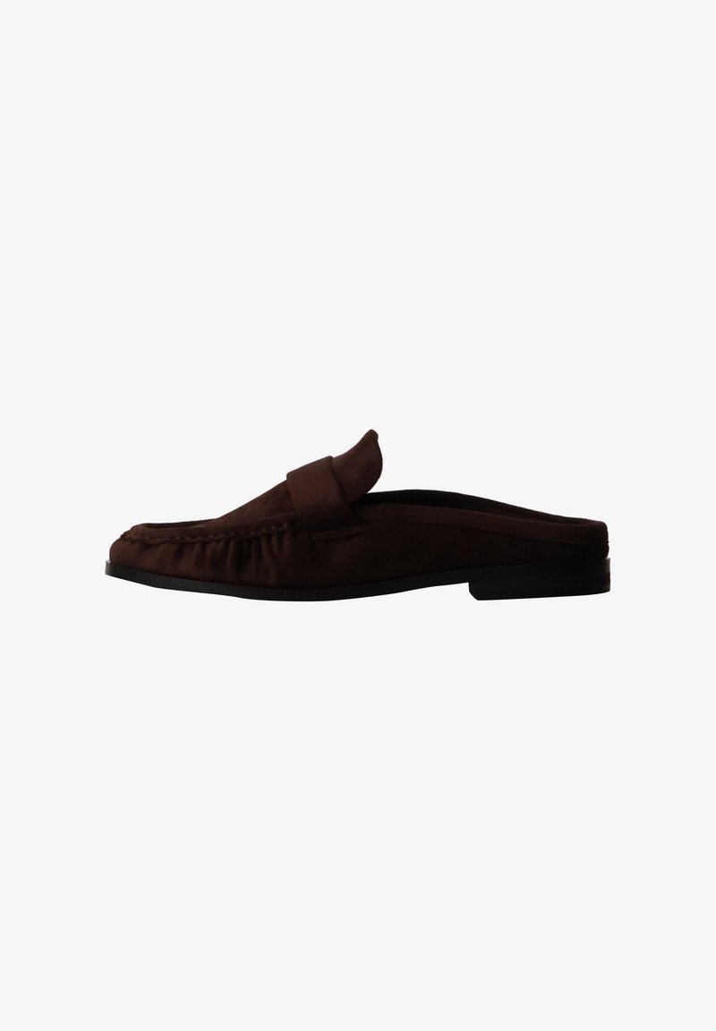 Mocassin mule en daim marron foncé à enfiler avec un petit talon et des coutures style mocassin sur fond blanc.