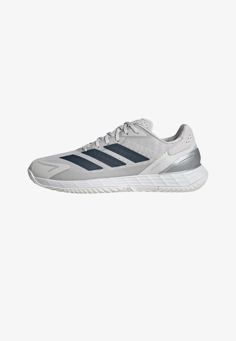 Hellgrauer Sportschuh mit dunkelgrauen Streifen, Mesh-Obermaterial, weißer Sohle und metallischer Fersenstütze, seitlich gezeigt.