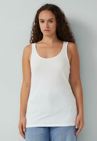 Witte tanktop met een ronde hals en brede schouderbanden, gemaakt van een gladde, rekbare stof. Eenvoudig ontwerp, aansluitende pasvorm.