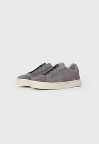 Zapatillas de ante gris con punta redonda y cordones elásticos, que cuentan con una suela de goma blanca y un diseño minimalista.