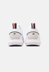 Sneaker bianche con tomaia in mesh, accenti in suede e suola in gomma nera. Fascette per il tallone a righe rosse e blu; patch con logo sulla parte posteriore.
