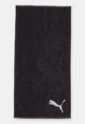 Asciugamano nero realizzato in morbido tessuto fluffy, con un logo Puma bianco nell'angolo inferiore e una sottile bordatura grigia lungo la parte superiore.