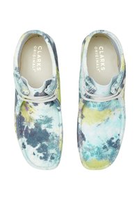 Zapatos Clarks Originals en un patrón de tie-dye con tonos de azul, verde y gris; material de ante suave con un diseño simple y cordones grises.