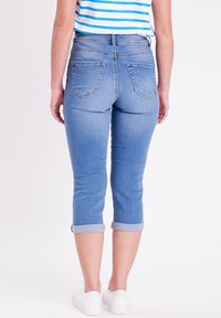 Pantalones capri de mezclilla azul claro con un diseño ajustado, dobladillos cuffed y dos bolsillos traseros. Textura suave y estilo clásico de cinco bolsillos.