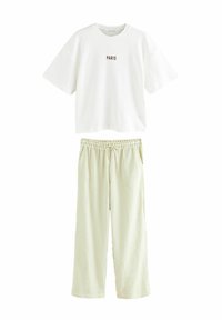 Vit kortärmad t-shirt med "PARIS" tryckt i brunt; kombinerad med ljusgröna, texturerade, vida byxor med elastisk midja.