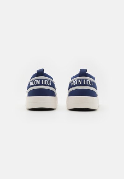 Adidași Blue Moon Boot cu vârful rotund, talpă albă și branding bicolor pe călcâi. Au un superior din țesătură și un tab de tragere.