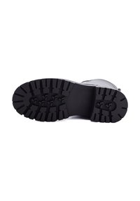 Suela de bota de goma negra con surcos profundos para tracción, diseño de superficie plana, puntera reforzada y un área de talón suave.