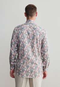 Overhemd met lange mouwen van licht materiaal met een bloemmotief in roze en blauwe bloemen op een grijze achtergrond. Rechte kraag en afgeronde zoom.