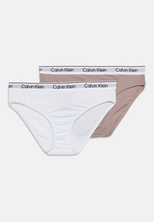 To Calvin Klein bomullstruser i hvitt og beige med merkevarede strikk i livet, lagt flatt på en hvit bakgrunn.