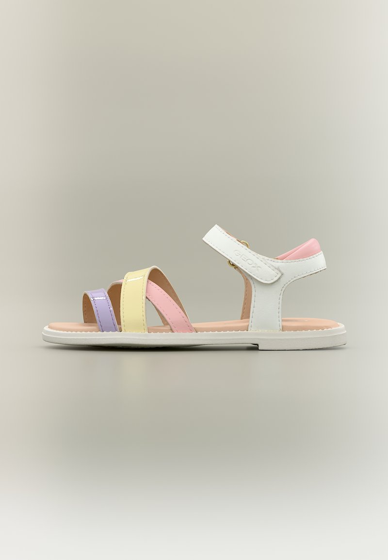Άσπρο σανδάλι με λουριά σε παστέλ μωβ, κίτρινο και ροζ χρώμα και ροζ μαξιλαρωμένο λουρί στη φτέρνα, πάνω σε ουδέτερο φόντο.
