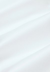 Biała tkanina o gładkiej, lekko teksturowanej powierzchni z ukośnym wzorem prążków, ukazująca miękkie zmarszczki i fałdy.