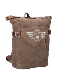 Brown canvas roll-top backpack with adjustable straps, silver hardware, cream logo print, and a side zip pocket. Durable and textured finish.