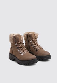 Braune Wanderschuhe mit einem weichen Kunstfellkragen, Schnürung und Metallösen. Dicke Gummisohle für besseren Halt. Reißverschluss an der Seite für einfachen Zugang.