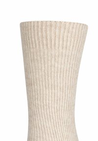 Calza a coste beige con una texture morbida, caratterizzata da righe verticali e un bordo aderente sulla parte superiore, progettata per comfort e calore.