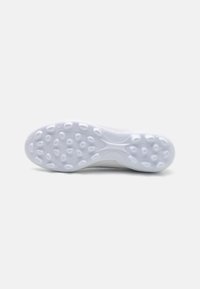 Sole di scarpa atletica bianca e lucida con una superficie texturizzata e modelli di presa circolari; progettata per trazione e stabilità.