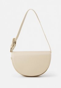 Sac à main en cuir beige de forme arrondie, avec un devant plat, une bandoulière réglable et des coutures visibles le long des bords. Design minimaliste.