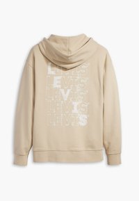 Sudadera beige con un gran patrón de logo en blanco "LEVIS" en la parte posterior. Está hecha de una tela suave, con capucha y puños acanalados.