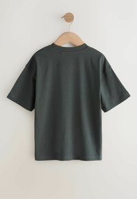 Ciemnoszary T-shirt z krótkim rękawem i okrągłym dekoltem, wykonany z gładkiej tkaniny, wiszący na drewnianym wieszaku na jasnym tle.