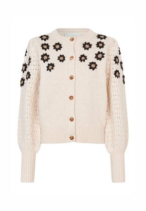 Strickjacke in hellem Beige mit floralem Mesh in Schwarz und Gold. Sie hat einen runden Hals, Holzknöpfe und gerippte Bündchen.