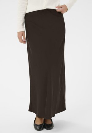 Lange braune Skirt aus glattem Stoff, mit gerader Silhouette und breitem Bund, kombiniert mit schwarzen flachen Schuhen.