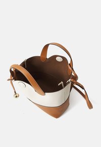 Sac seau en cuir tan avec des accents crème, texture lisse, bords arrondis, ouverture en haut, poche zippée intérieure et quincaillerie en or.