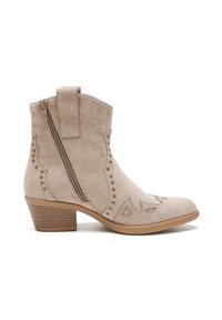 Botas de tobillo de ante beige con cremallera lateral, costuras decorativas y tachuelas de metal. Tienen un tacón de bloque de madera y punta redondeada.