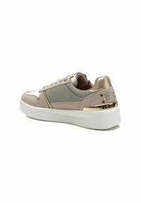 Zapatillas con parte superior de ante beige y cuero liso. Presenta acentos en gris claro, detalle metálico en la parte trasera y una suela gruesa blanca.