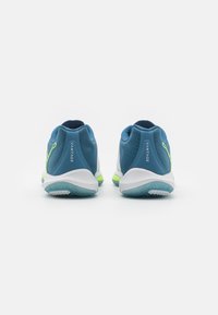 Scarpe da atletica blu con una parte superiore testurizzata, dettagli bianchi e verdi, tacco arrotondato e suola in gomma con un motivo a zigzag.
