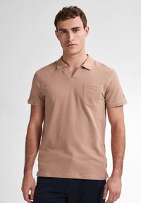 Hnědá polo košile vyrobená z texturované bavlny, s klasickým límečkem, krátkými rukávy a náprsní kapsou. Jednoduchý design, bez vzorů.