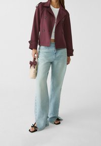 Bordeaux dubbelmatig jasje, cropped ontwerp, lichtblauwe wijde jeans met zijknopen, zwarte sandalen, kleine beige tas met een patroonstrik.