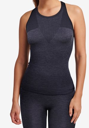 Mujer con top deportivo sin costuras y sin mangas en gris oscuro y leggings a juego, mostrada desde el cuello hasta las caderas sobre un fondo blanco.