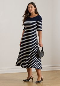 Navy striped midi dress with short sleeves, cotton blend fabric, flared silhouette, paired with black slingback heels and a mini handbag.