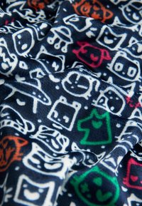 Tkanina polarowa o ciemnogranatowym tle z kolorowymi, zabawnymi rysunkowymi twarzami i kształtami w kolorach białym, zielonym, różowym i pomarańczowym.