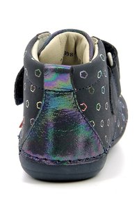Black children's boot with multicolored dotted pattern, velcro strap, textured finish, and cushioned interior, featuring a rounded toe design.