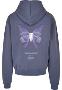 Sweat à capuche bleu marine avec un motif ailes de papillon violettes et des lettres blanches stylisées "MG" au dos, ainsi qu'un petit texte blanc et une illustration de zèbre en dessous.