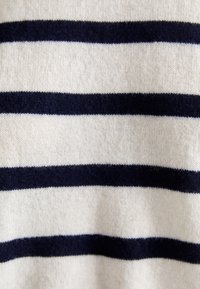 Světle zbarvený pletený textil s tmavě modrými vodorovnými pruhy. Měkká textura, rovnoměrný vzor, střední tloušťka, neformální design.